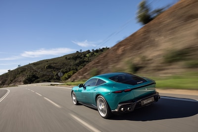 Ferrari Amalfi verde turquesa, vista trasera tres cuartos en movimiento sobre carretera con colinas
