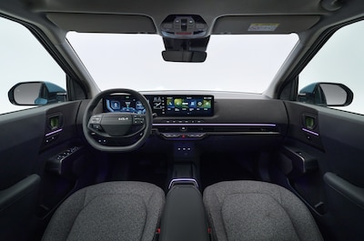 Interior del Kia EV2, volante con logo Kia, triple pantalla digital y detalles morados
