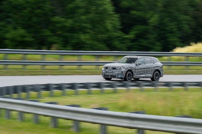 Prototipo camuflado del BMW iX5 2026 vista frontal en movimiento sobre pista de pruebas en Spartanburg, Carolina del Sur