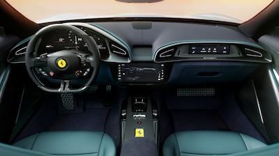 Interior completo del Ferrari Amalfi, volante con logo, tres pantallas digitales y asientos azul petróleo.