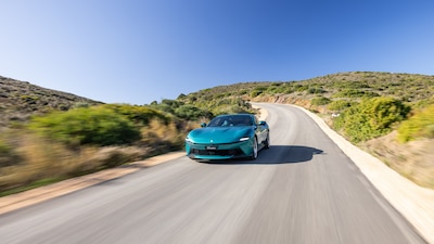 Ferrari Amalfi verde turquesa, vista frontal en movimiento sobre carretera sinuosa.