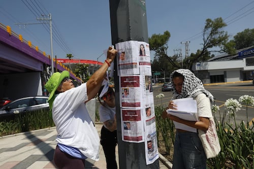 Familias de personas desaparecidas pegan fichas de búsqueda en el Estadio CDMX