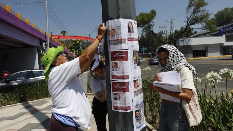 Familias de personas desaparecidas pegan fichas de búsqueda en el Estadio CDMX