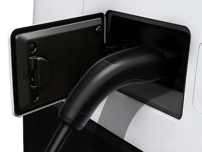 Detalle del puerto de carga eléctrica del Olinia Uno con conector negro tipo doméstico abierto, batería LFP de 14.7 kWh compatible con enchufes de 110V y 220V