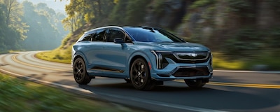 Cadillac Optiq V 2026 azul metalizado en movimiento sobre carretera SUV eléctrico deportivo 519 hp doble motor eléctrico 0 a 100 kmh en 3.8 segundos gama V-Series