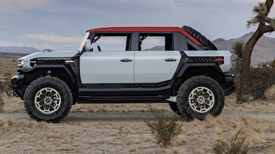 GMC HUMMER X concept pickup bicolor blanco y techo rojo vista lateral completa estacionado en desierto con llantas off-road de gran tamaño rines beadlock y salpicaderas desmontables concepto de diseño avanzado de General Motors sin destino de producción
