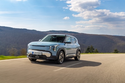 Kia EV2 Frost Blue en movimiento por carretera de montaña, placa alemana, versión europea distinta a la unidad colombiana probada
