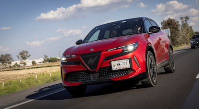 Alfa Romeo Junior 2026 color rojo vista frontal en movimiento sobre carretera mexicana SUV híbrido mild hybrid 48V con parrilla triangular Scudetto y faros LED en configuración 3+3 motor 1.2 litros turbo 145 hp tracción delantera