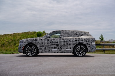 Prototipo camuflado del nuevo BMW X5 2026 vista lateral estática en carretera durante pruebas de ingeniería en Spartanburg