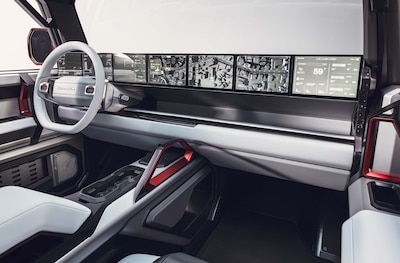 Interior GMC HUMMER X concept mostrando volante blanco con logo HUMMER pantalla panorámica de múltiples displays con mapas navegación y datos del terreno consola central con detalles en rojo y acabados bicolor blanco y negro parte del ecosistema digital HUMMER HUB