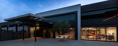 Exterior nocturno del estudio de diseño avanzado de General Motors en Pasadena California campus de 13750 m² con concept cars iluminados visibles a través de ventanales de vidrio sede donde fue concebido el GMC HUMMER X